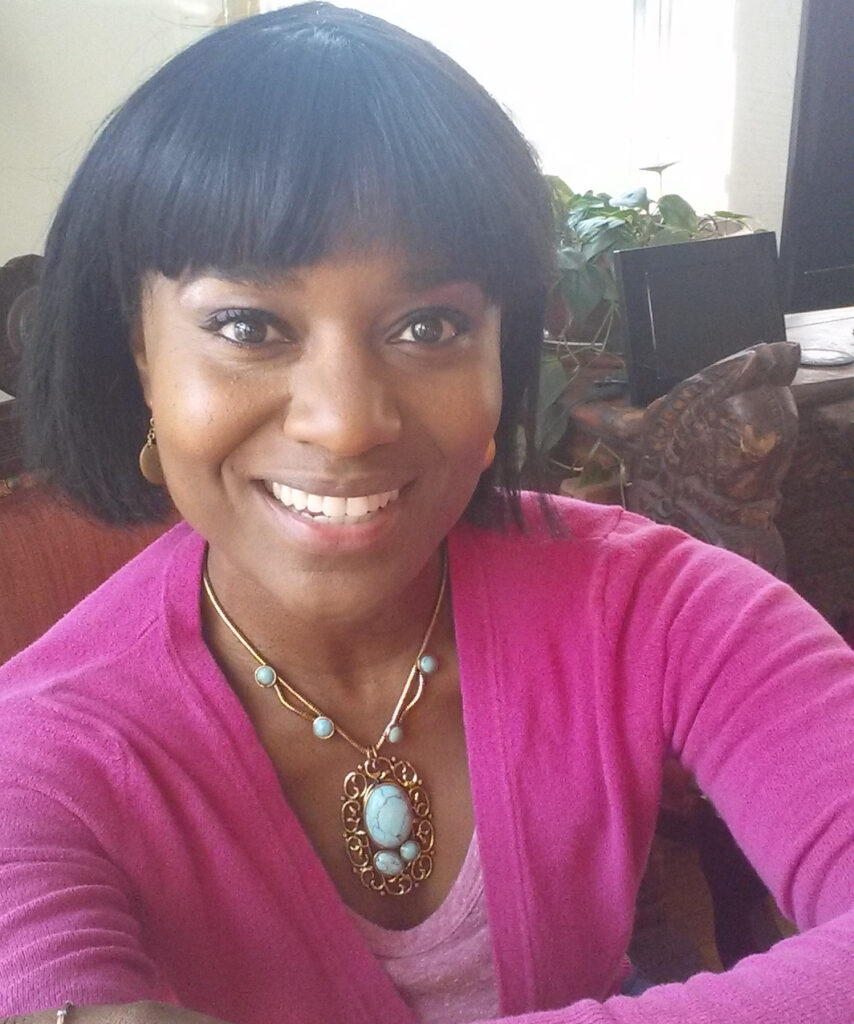 Ife Oshun wears a pink sweater and smiles at the camera